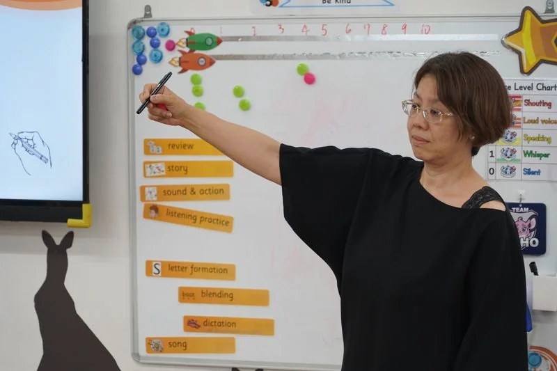 Atsuko Maruyama holding up a pen to demonstrate hand movements during training