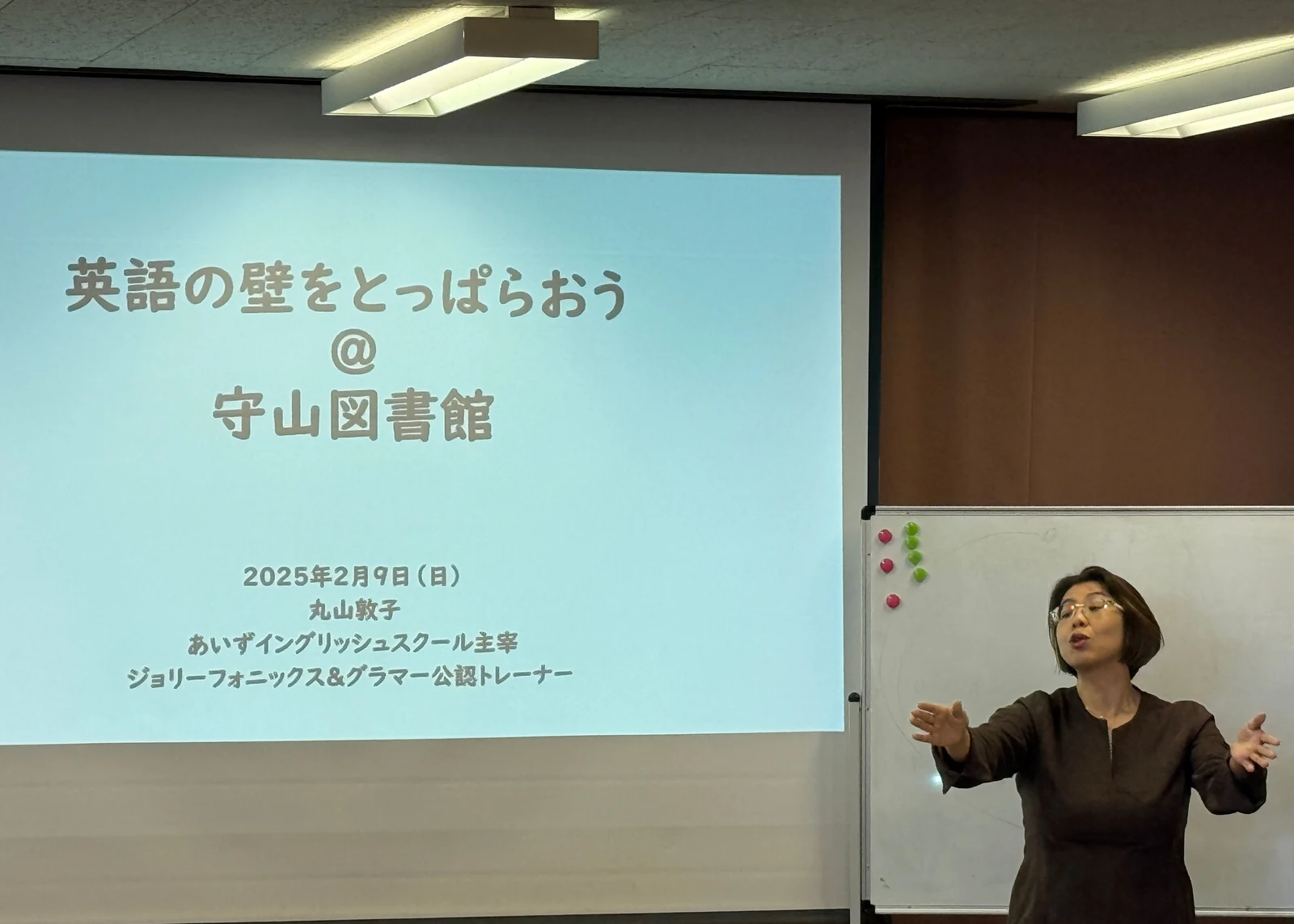 Atsuko Maruyama presenting beside the seminar title slide at Moriyama Library in Nagoya