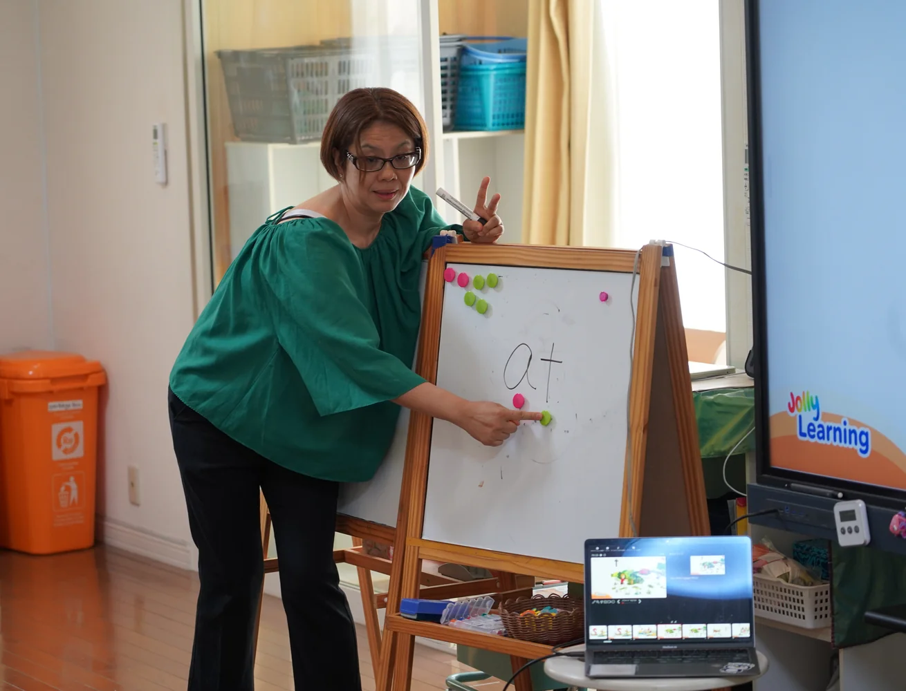 Atsuko Maruyama using “at” and coloured magnets on a whiteboard to explain sounds and letters
